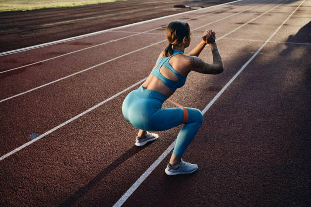 A woman in a running field, stretching before starting unning rounds